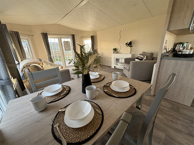 Image of a table with glasses, bowls and a plant on inside a static caravan