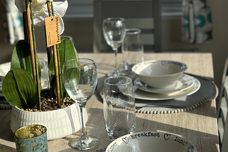 Image of a table with glasses, bowls and a plant on inside a static caravan